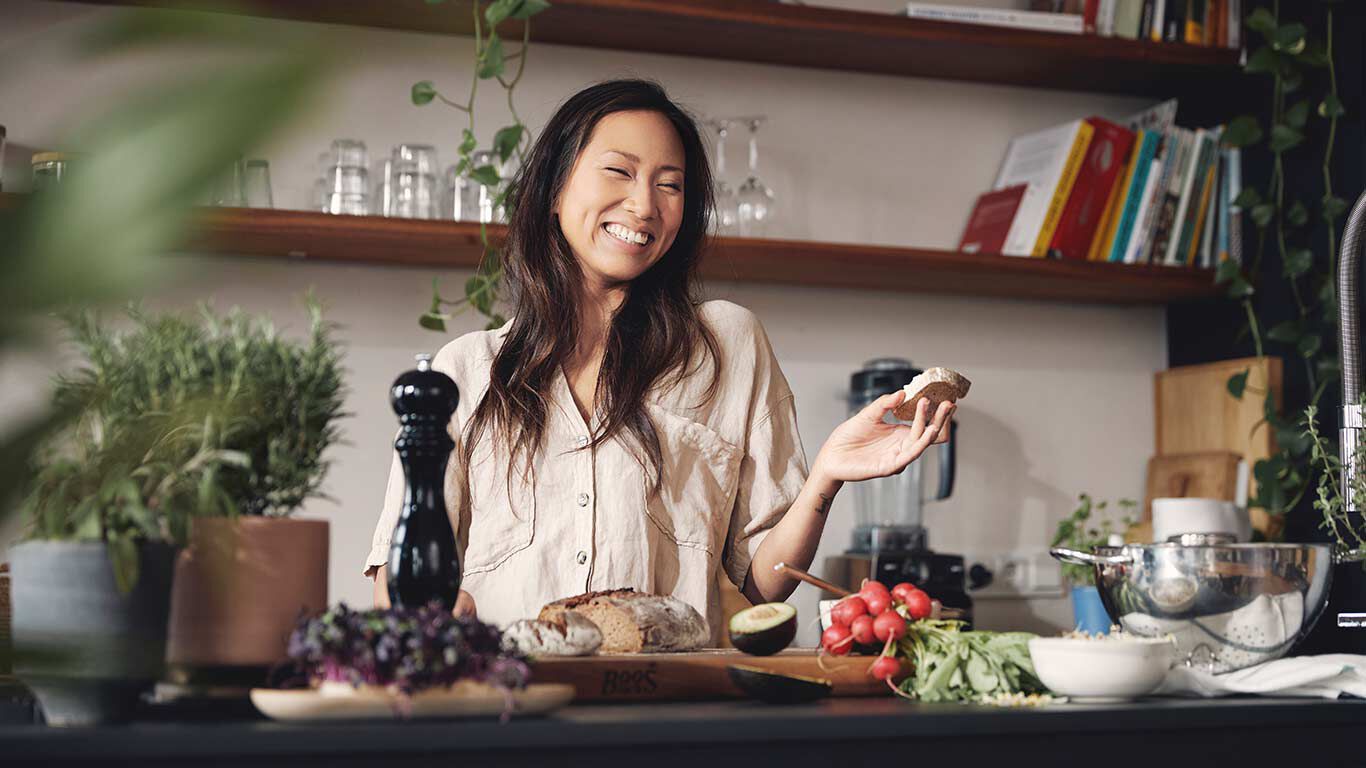 Une femme se tient dans la cuisine et savoure son repas. 